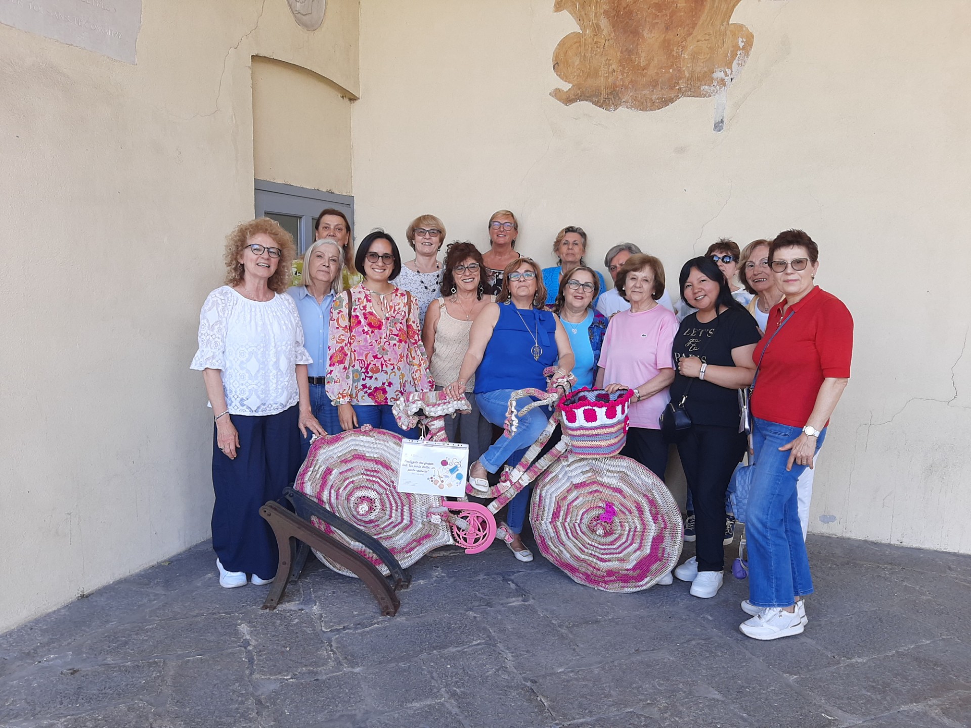 l'assessora Valentina Giro con le bibliotecarie e le signore del Gruppo Knit mostrano la bicicletta rivestita con lavori a maglia