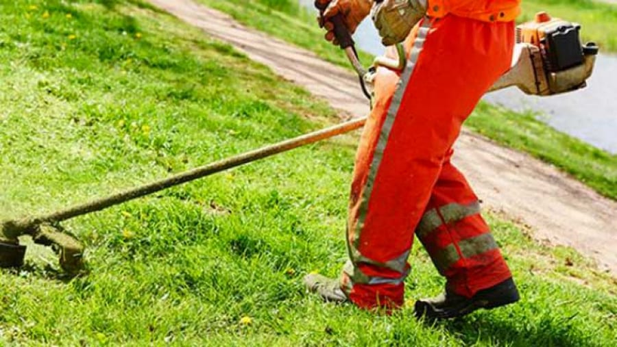 Addetto allo sfalcio del verde mentre taglia l'erba 